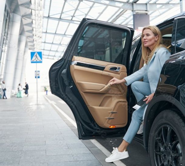 Gut gekleidete Frau steigt aus Flughafentaxi